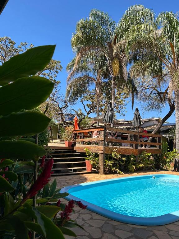 a swimming pool in a yard with palm trees at Pousada Anauê Cipó in Serra do Cipo