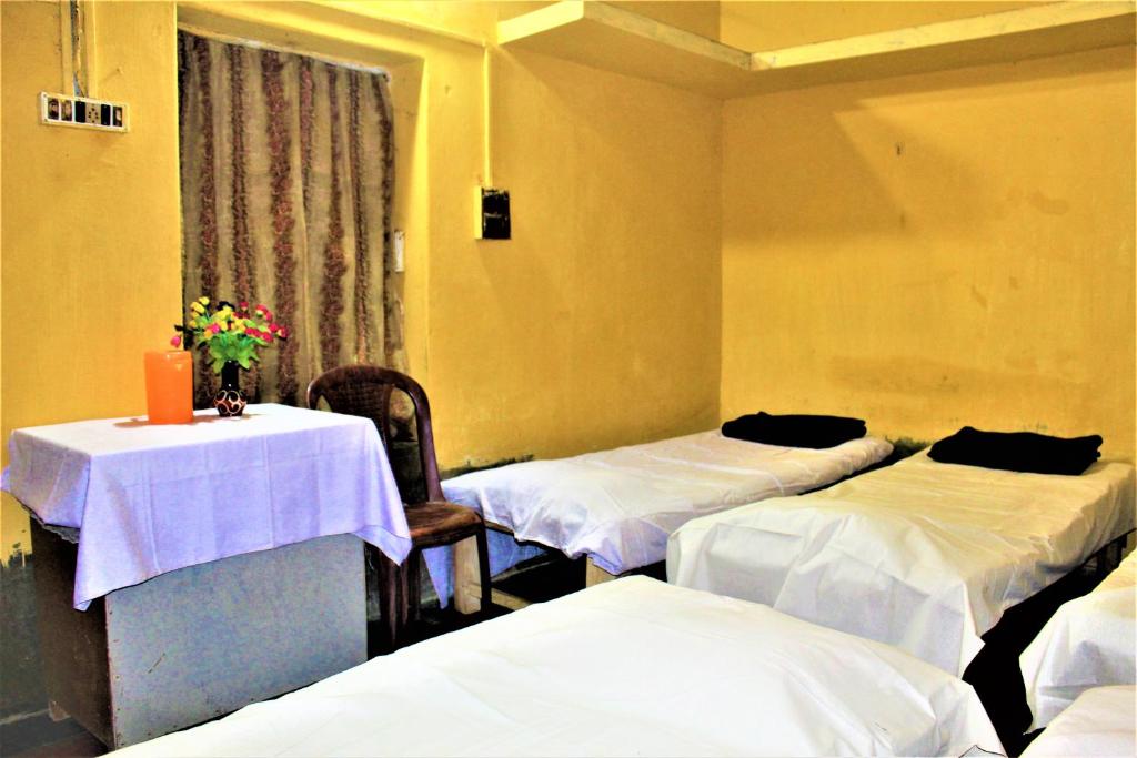 a room with two beds and a table with flowers on it at The OLD house in Bolpur