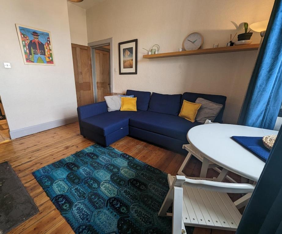 a living room with a blue couch and a table at Cosy 1 bedroom flat close to city centre in Edinburgh