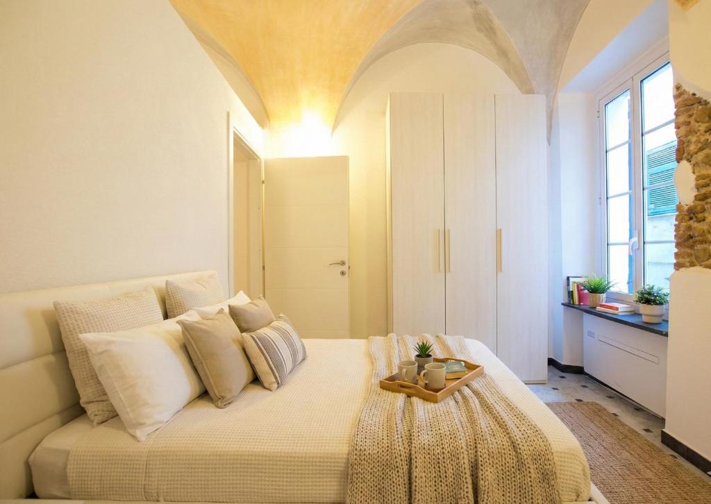 Rivierarent Borgo Basecamp 10 في فينالي ليغوري: غرفة نوم مع سرير عليه صينية