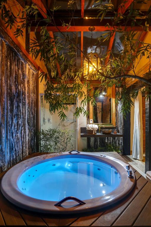 波苏斯-迪卡尔达斯Pousada Trem Chic的植物客房内的大型按摩浴缸