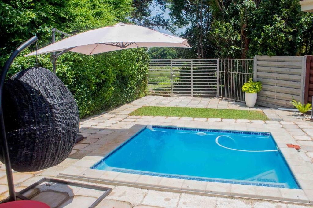 a swimming pool with an umbrella and an umbrella at Serenity in Hartbeespoort