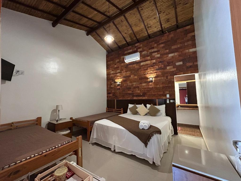 a bedroom with a bed and a brick wall at Pousada Meraki in Serra do Cipo