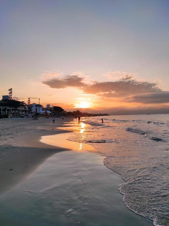 una puesta de sol en una playa con gente caminando en el agua en Apartamento com churrasqueira 400 metros da praia, en Florianópolis