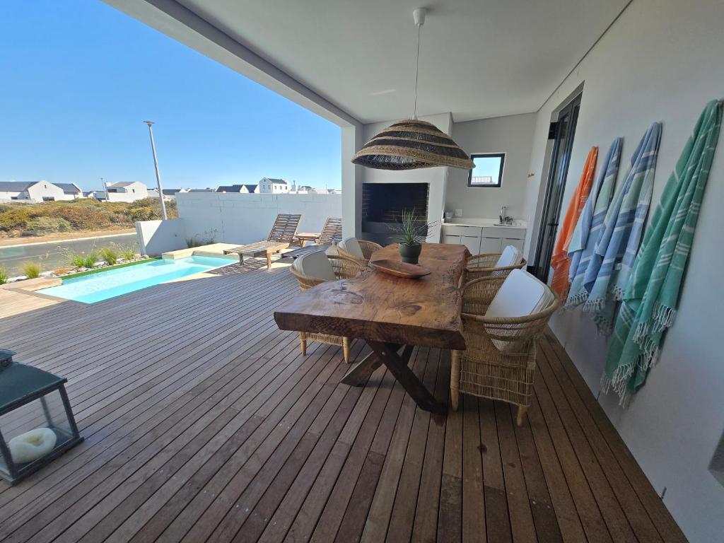 a patio with a wooden deck with a table and chairs at Yzer Heights Relaxed Luxury Stay in Yzerfontein