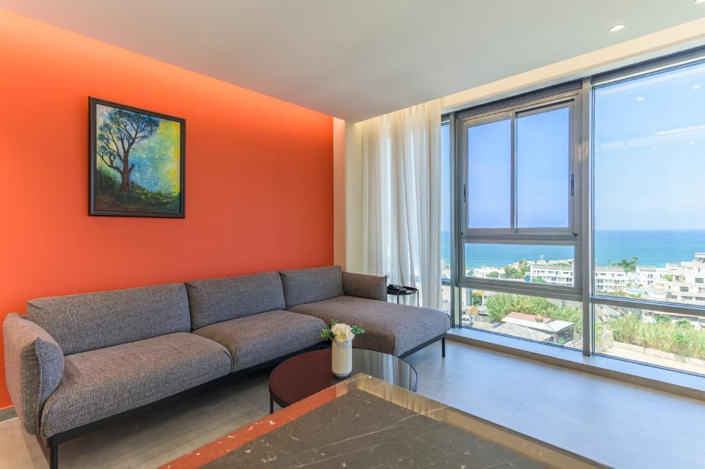 un soggiorno con divano e parete arancione di Germac Suites a Al Kaslīk