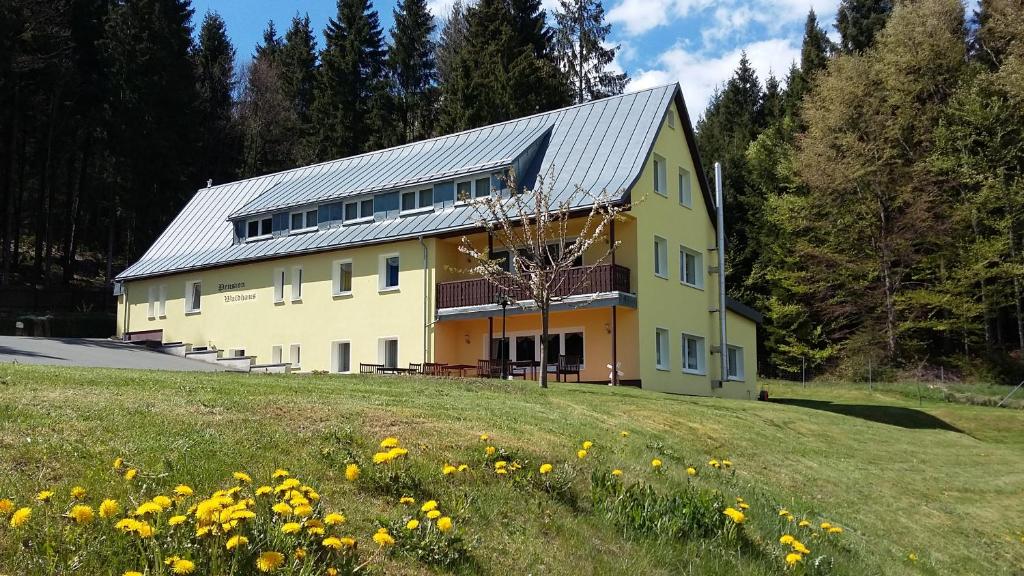 a yellow building on a hill with a field of flowers at Pension Berghof in Breitenbrunn