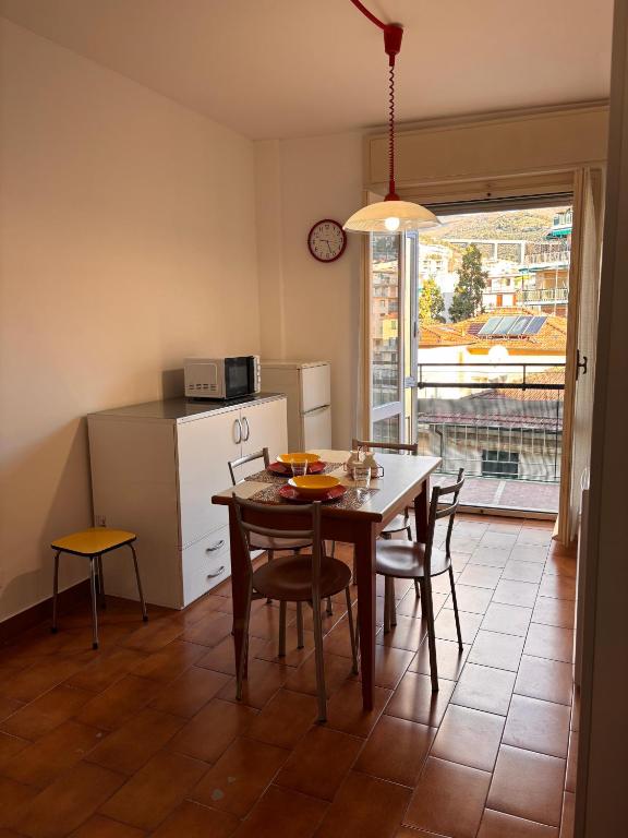 una cucina con tavolo e sedie e una cucina con finestra di Casa Arcobaleno a Sanremo