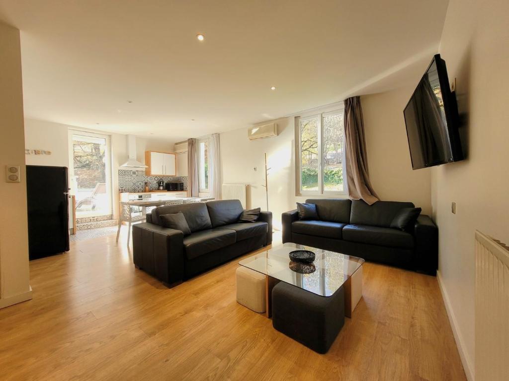 a living room with two black couches and a coffee table at Résidence Andurans - Pyrénées Resort in Argelès-Gazost