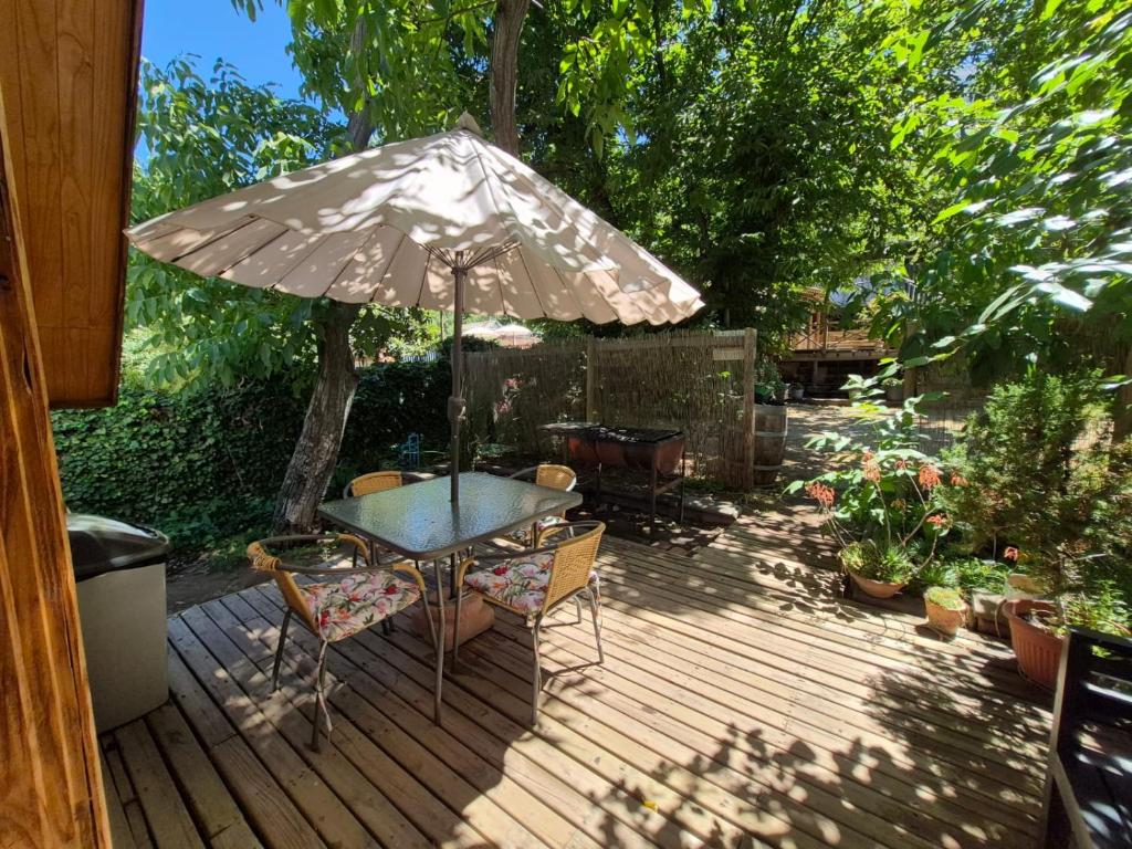 a table and chairs with an umbrella on a deck at Carolin Cacao - Cabaña Nogal in San José de Maipo