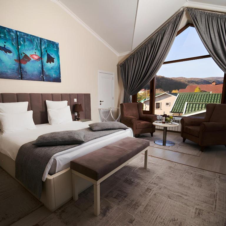 a bedroom with a bed and chairs and a large window at AlmaBagi Hotel&Villas in Quba