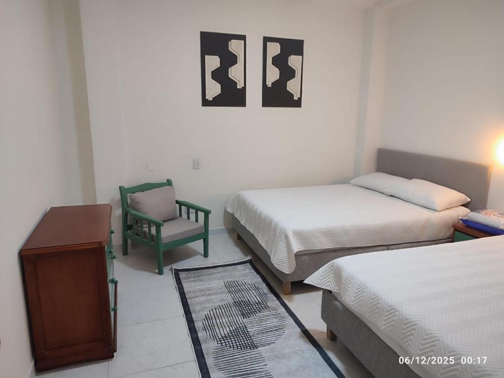 um quarto com duas camas e uma cadeira em Consentir apto 2 alcobas em Pereira