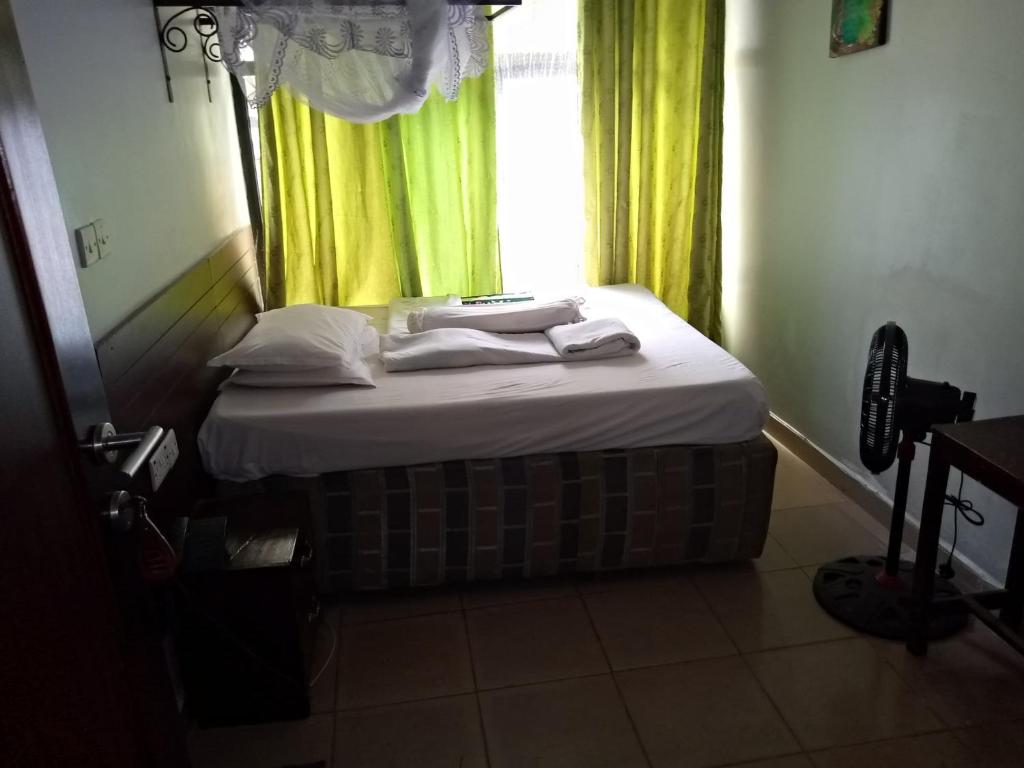 布科巴WalkGard WestLand HOTEl的一张位于带绿窗帘窗户的房间里的床