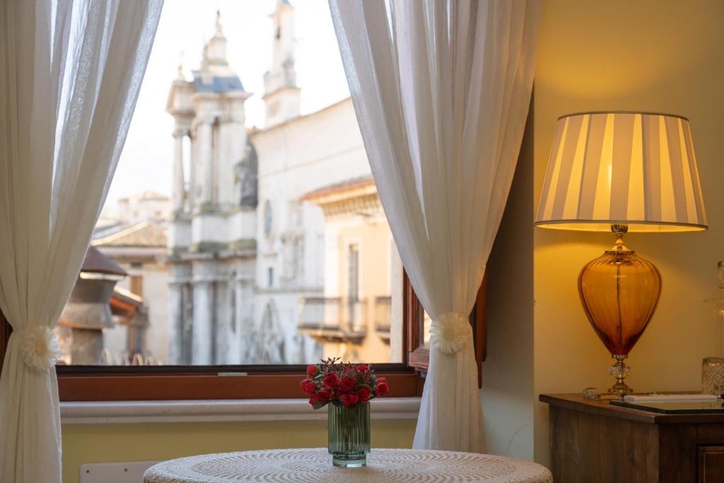 Room & Breakfast La Dimora في سولمونا: إناء من الزهور على طاولة أمام النافذة