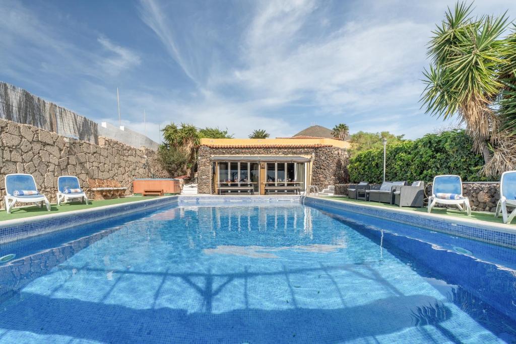 a swimming pool with chairs and a house at Finca Toledo in Las Zocas