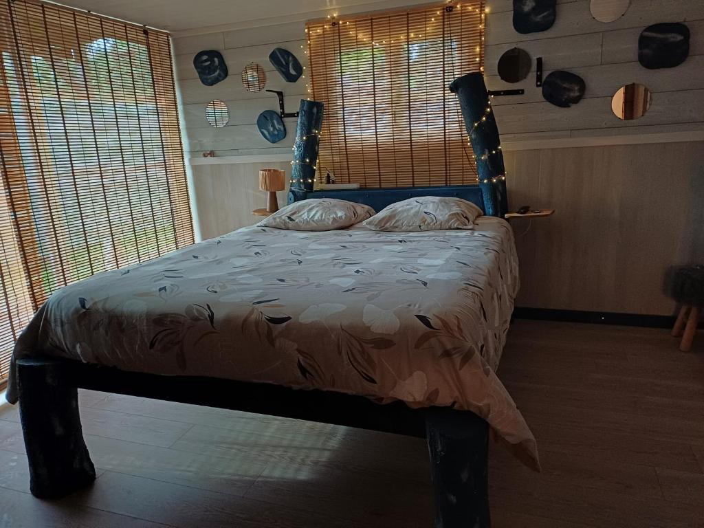 a bedroom with a bed in a room with windows at aud eau maillet in Tilques