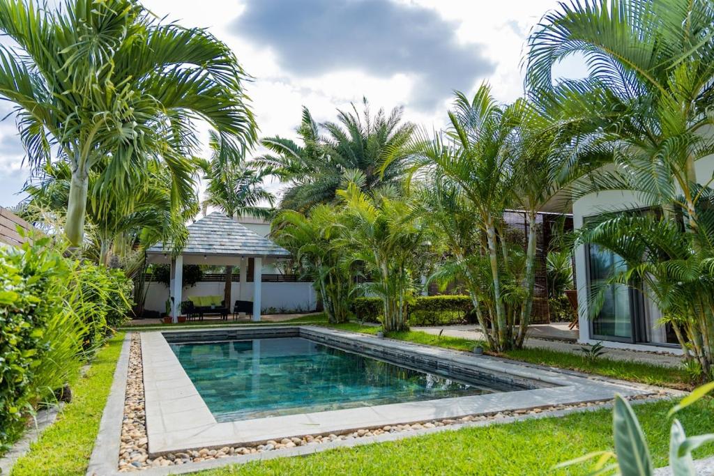 a swimming pool in front of a house with palm trees at Summer Palms Villa in Flic-en-Flac