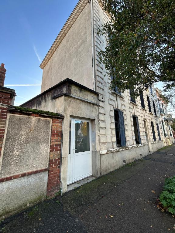 an old brick building with a white door on a street at Le petit cocon in Sens