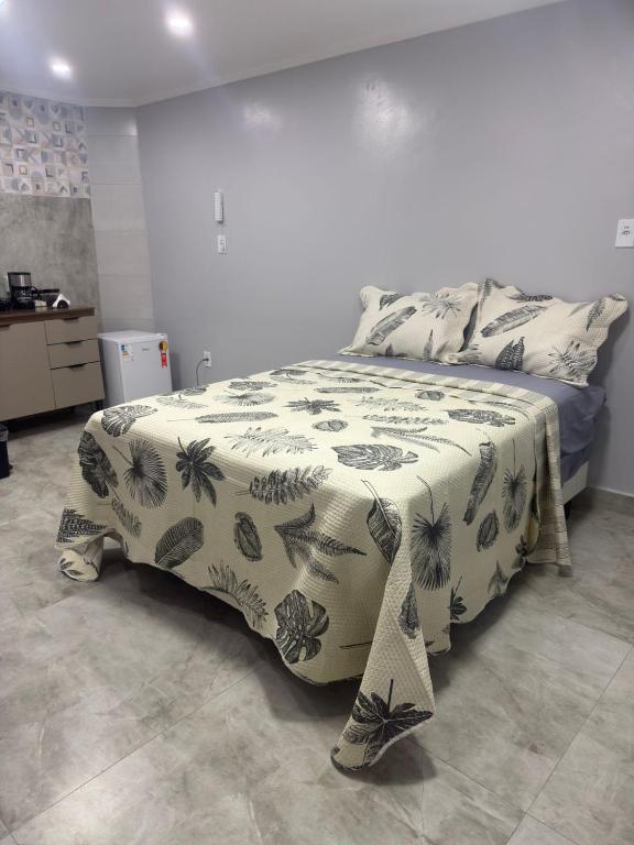 a bedroom with a bed with a black and white blanket at Suíte Doce Recomeço da Alice in Arraial do Cabo