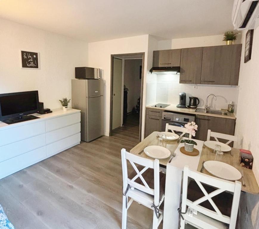 une cuisine avec une table et des chaises dans une pièce dans l'établissement Charmant studio climatisé 24 m2 terrasse à 100m de la plage, à Saint-Mandrier-sur-Mer