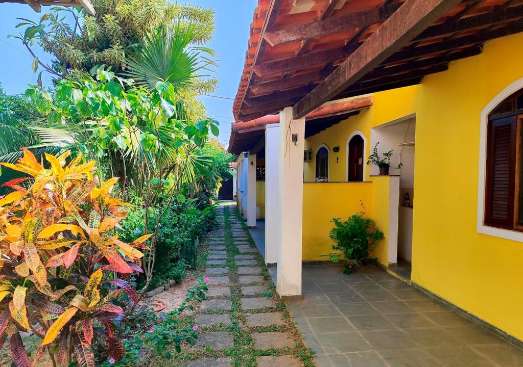 ein gelb-weißes Gebäude mit einem Gehweg in der Unterkunft Suítes Jaconé - Saquarema in Jaconé