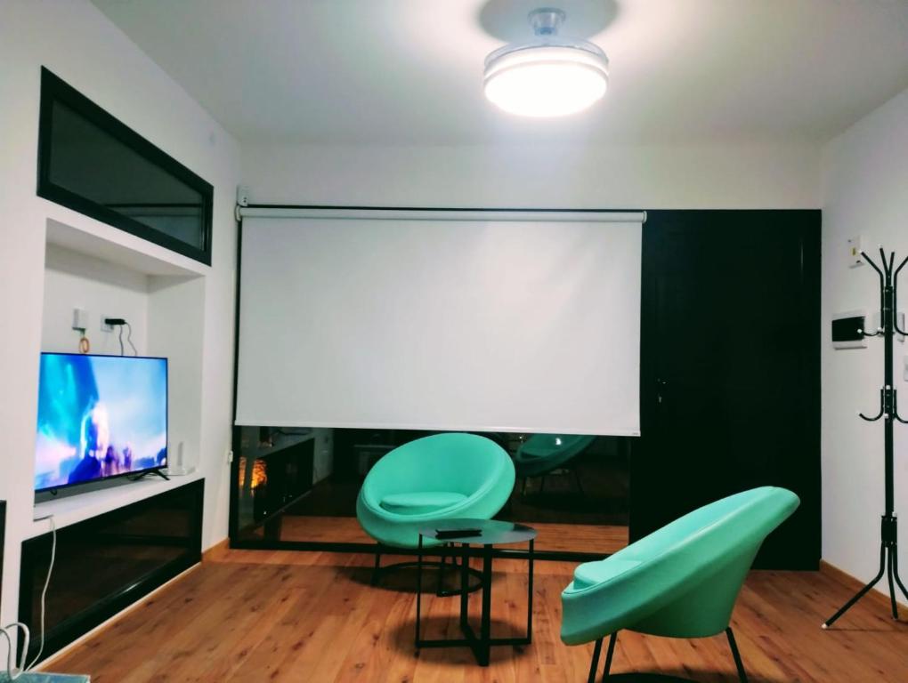 a room with two green chairs and a white projection screen at Big Sur in Mar Azul