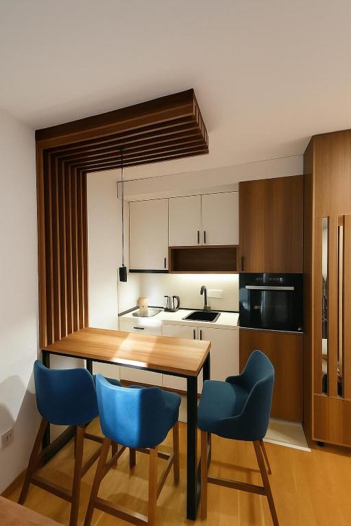a kitchen with a wooden table and blue chairs at Apartman Felicita 2 Zlatibor in Zlatibor