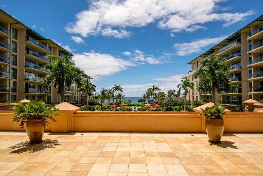 a view of a resort balcony with palm trees and the ocean at Honua Kai H237 in Kaanapali Airport