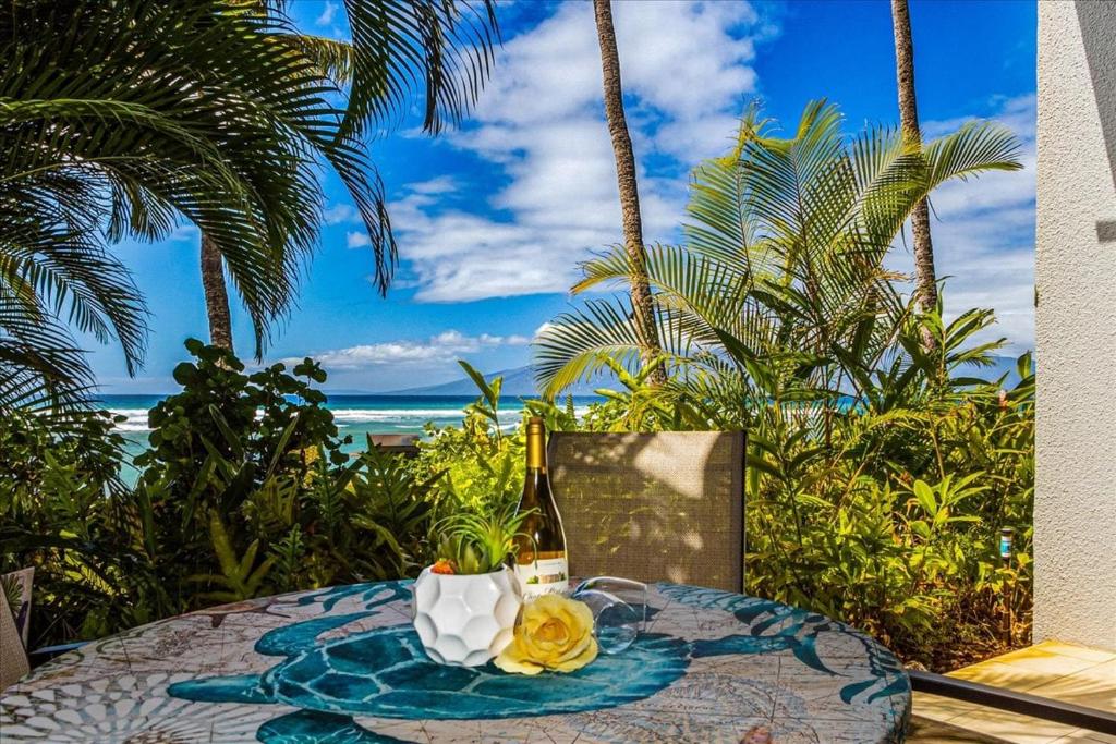 a table with a bottle of wine and a glass at Hale Mahina A102 in Kahana