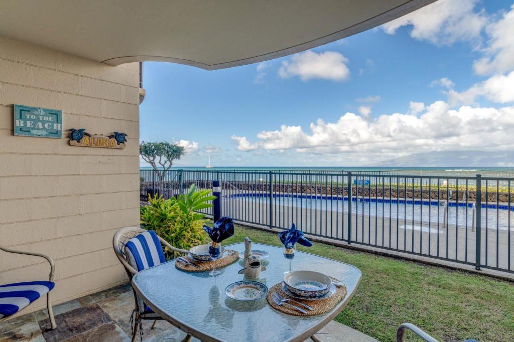 a patio with a table and chairs and a view of the ocean at Kahana Reef 106 in Kahana