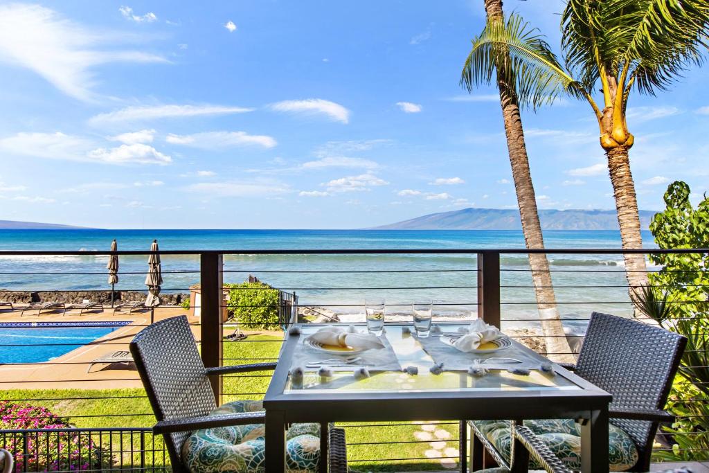 a table on a balcony with a view of the ocean at Hale Kai 220 in Kahana