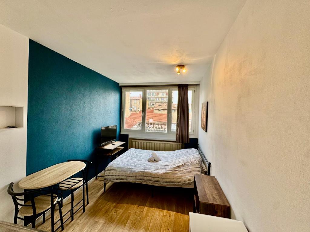 una pequeña habitación con una cama y una mesa en Hyper Centre de Valence - Studio N32, en Valence