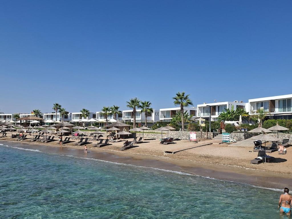 a beach with chairs and umbrellas and the ocean at Spacious & Bright 2BR Apartment, 5min to Beach in Boghaz