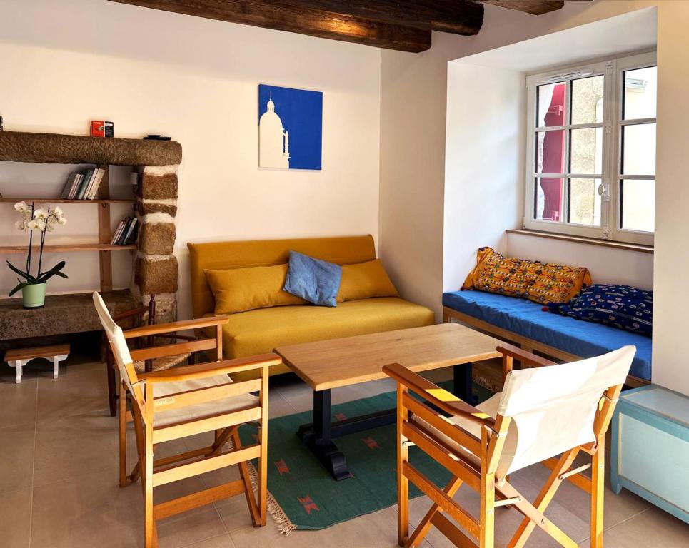 a living room with a couch and a table and chairs at Le clos du prieuré - Les Gîtes de la Côte d'Amour in Batz-sur-Mer