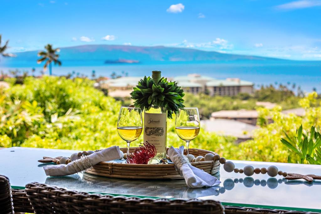 un tavolo con due bicchieri di vino e un cesto di cibo di Ekolu 911 a Wailea