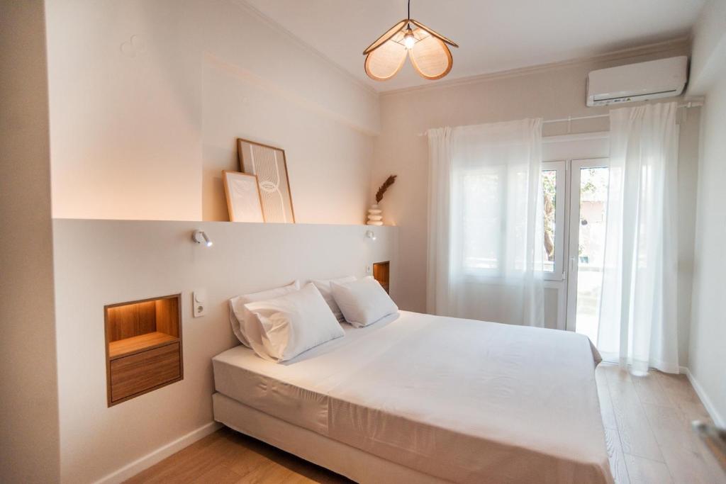 una camera da letto con un letto con lenzuola bianche e una finestra di 14 luxury apartment a Preveza