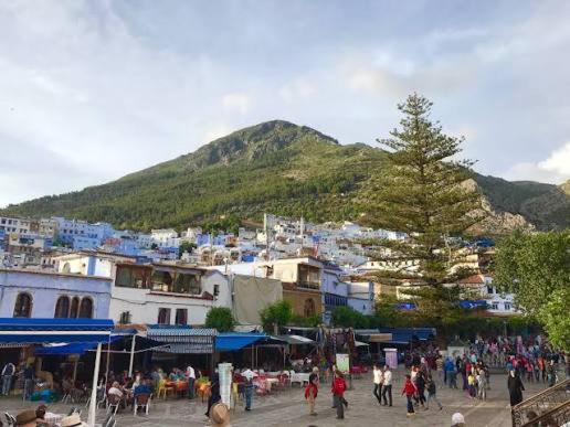 un grupo de personas caminando por un pueblo con una montaña en Dar amine, en Chefchaouen