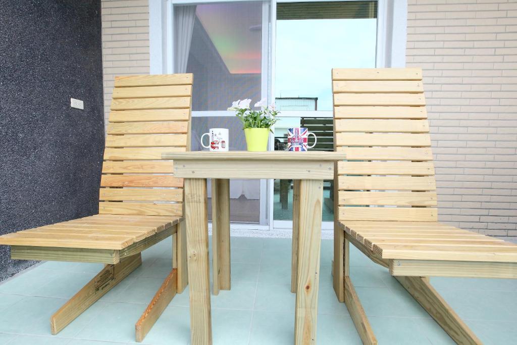 two wooden chairs and a wooden table and bench at Edinburgh 16 Inn in Hengchun
