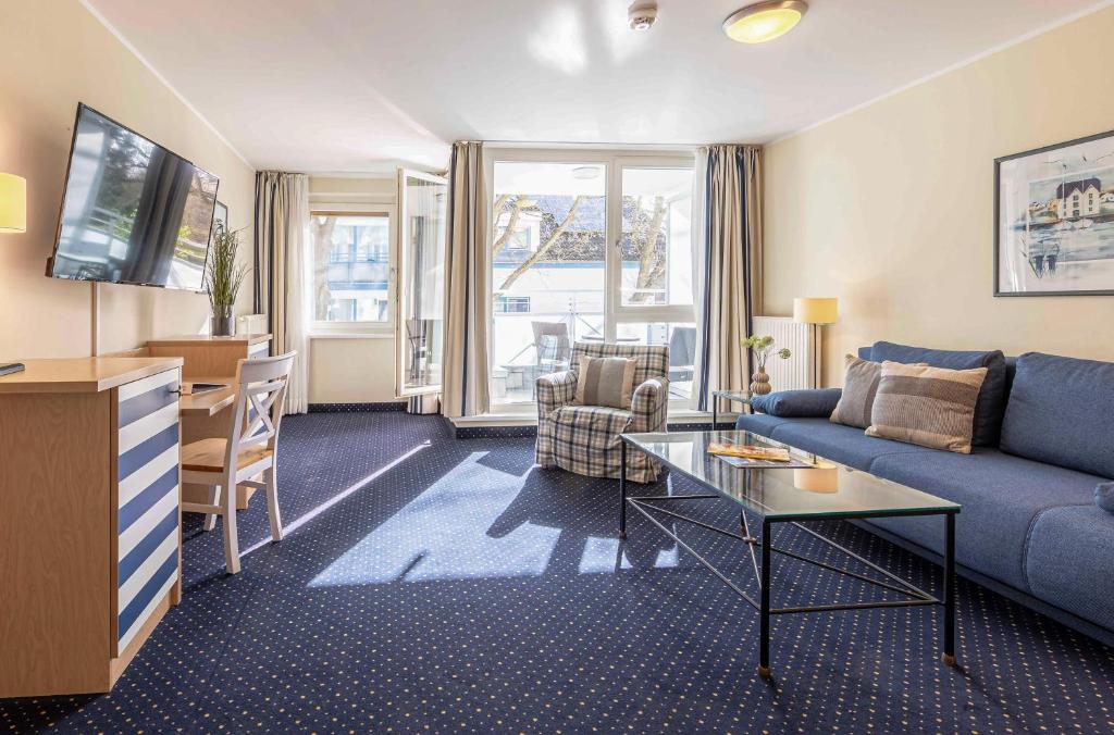 Ferienwohnung Deichperle - Ihr idyllischer Rückzugsort an der Ostsee in Zingst في زنغست: غرفة معيشة مع أريكة زرقاء وطاولة