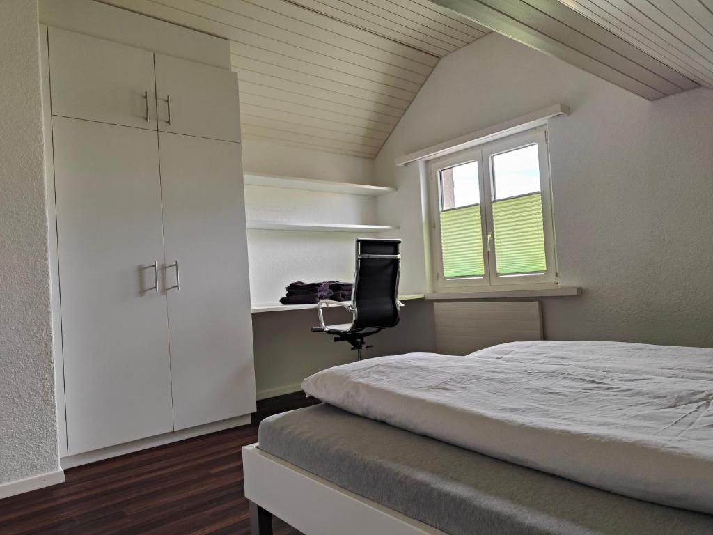 a bedroom with a bed and a desk and a window at Goldiger Berg - Pilatusweg 6 in Affoltern