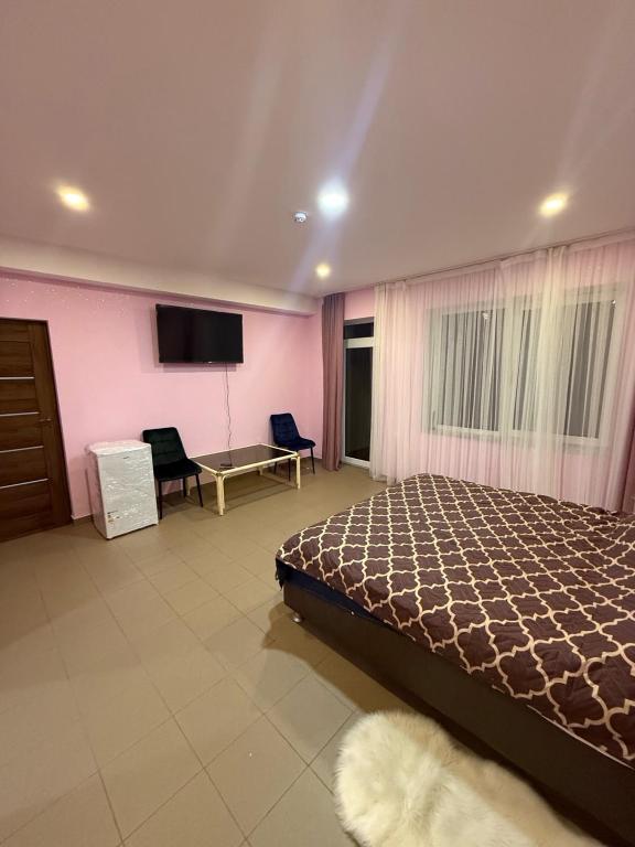 a bedroom with a bed and a flat screen tv at Bernotiškių Hotel & Dining 