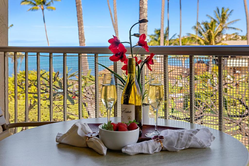 a table with a bottle of wine and a vase with flowers at Napili Shores H263 in Kapalua