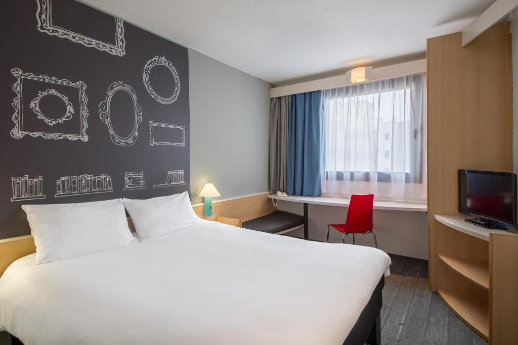 a room with a bed and a desk and a tv at Ibis Szczecin Centrum in Szczecin