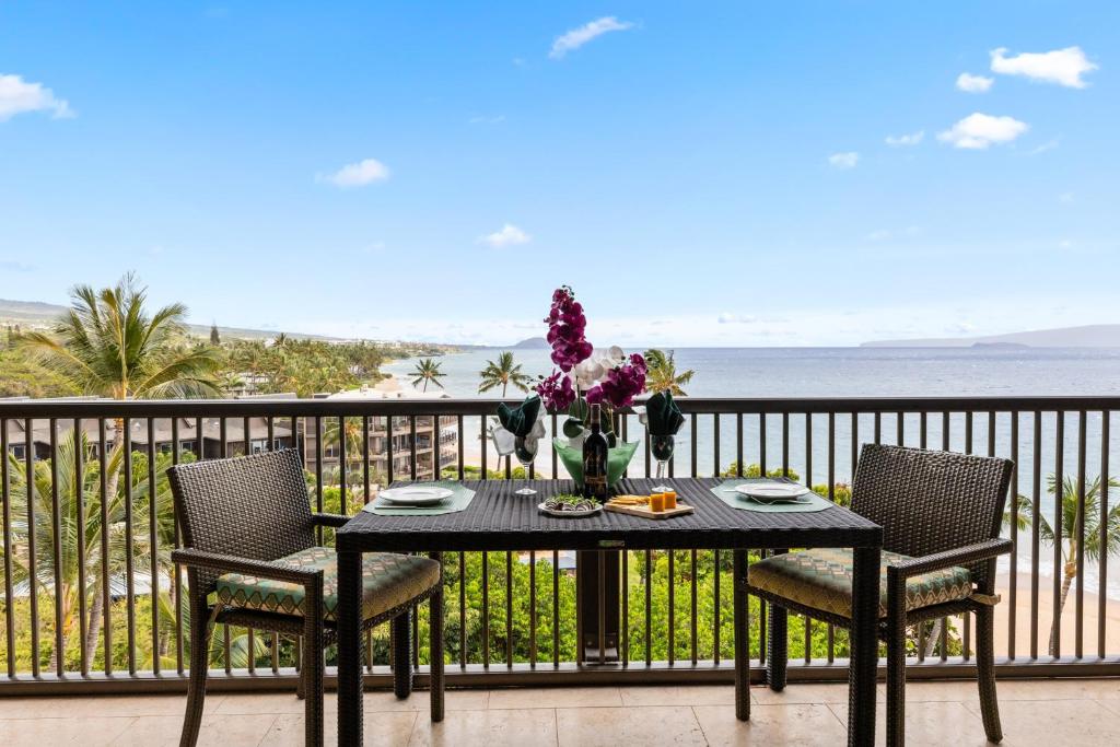 un tavolo nero con sedie e fiori sul balcone di Mana Kai 714 a Wailea