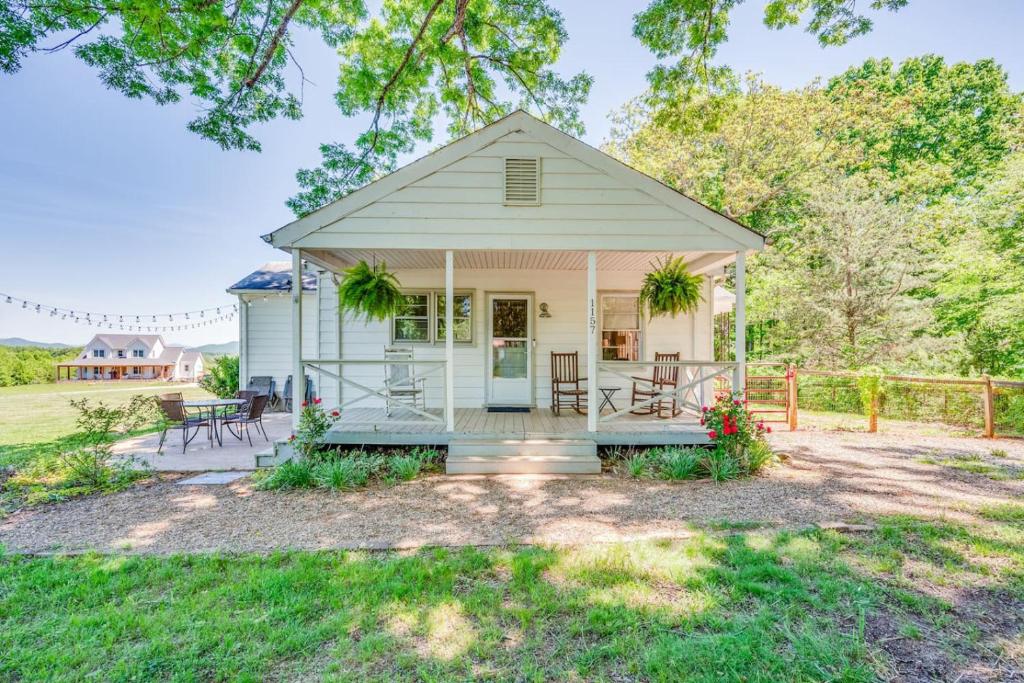 een klein wit huis met een veranda en stoelen bij Redwing Farm Cottage - Mountain Views and Firepit! in Goode