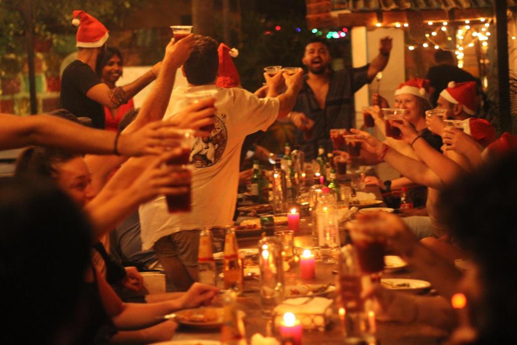 a group of people sitting around a table in christmas hats at The Beachside Hostel in Anjuna