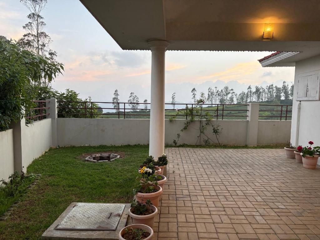 a patio with potted plants and a fence at Sathya Holidays Evermist Stay in Ooty