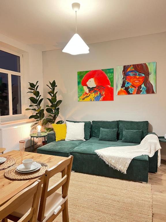 a living room with a green couch and two paintings at Liebe Wohnung Pension in Penig