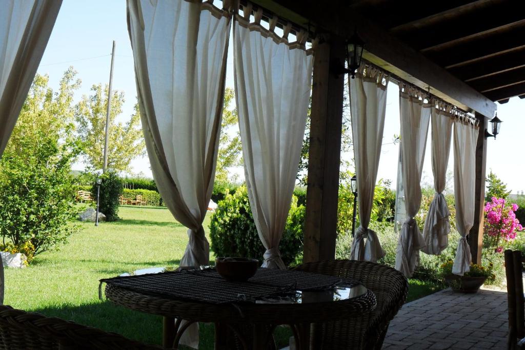 una mesa y sillas en un patio con cortinas blancas en Domus Aurea en Torrevecchia Teatina