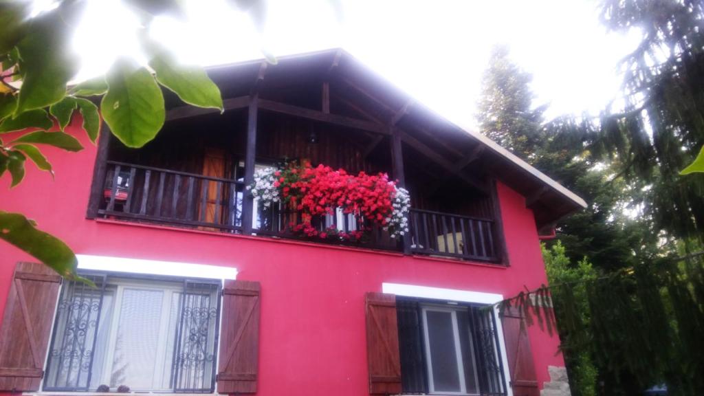 a pink house with a balcony with red flowers on it at B&B La Capanna Rossa in San Romolo